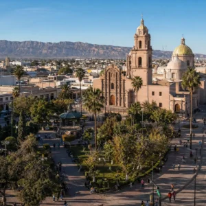 advanced cardio tennis — Gómez Palacio, Mexico seen from the slope of the Cerro de la Pila, the Laguna city spread below with its Eiffel Tower replica catching late desert light.
