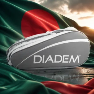 best cardio tennis lessons — the Diadem Tour V3 Tennis Bag (12 Racquet) composed into one image with the national flag of Bangladesh — a bottle-green field carrying a single red disc set slightly toward the hoist. A very large flag is streaming from a mast above an open ground in Mymensingh at sunrise, with the real sun coming up behind it over the Old Brahmaputra so that the disc and the sunrise sit in the same frame; a crowd is gathering below for a parade, drummers are warming up, boys are selling paper flags along the rope line and mist is lifting off the river. The bag stands alone on the grass directly beneath the mast, glowing faintly, carried by nobody.