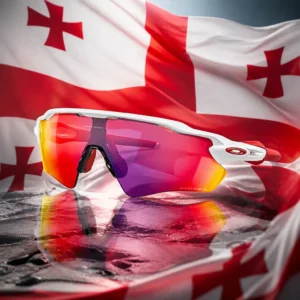 Beverly Heights cardio tennis classes — the Oakley Radar EV Path Shield Sunglasses composed together with the national flag of Georgia in one photoreal studio composition — the white field with its large red cross reaching all four edges and four small red bolnur-katskhuri crosses in the corners, filling the background in soft folds and lit from one side, with the sunglasses standing clear in front of it. Nobody wears, holds or uses it, and there are no words, letters, numerals or lettering of any kind anywhere in the frame.