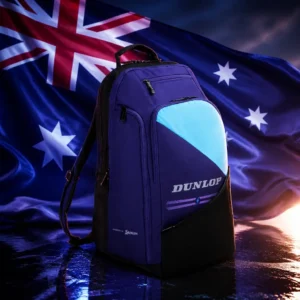 cardio classes Fort Lauderdale — the Dunlop FX Performance Tennis Backpack and the flag of Australia combined by the model into a single photoreal composition. The blue ensign fills the frame with the Union Jack in the upper hoist, the large seven-pointed Commonwealth Star beneath it and the five stars of the Southern Cross across the fly, the cloth pulled taut by a sea wind with side light raking the weave, and the black and blue backpack is composed into the arrangement so that its shaped shoulder straps and the star pattern read as one object, with no lettering anywhere in the picture.
