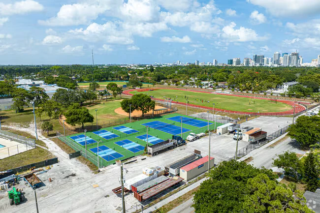 Aerial view of Stranahan High School in Fort Lauderdale showing the tennis courts, running track and ball field, with the downtown skyline behind.